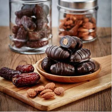 Chocodates and nuts on a wooden cutting board.