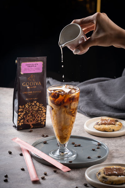 A person is pouring Godiva Chocolate Truffle Coffee 284g into a glass.