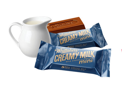 A jug of Whittaker's Creamy Milk Mini Slabs 180g and a bar of chocolate next to it.