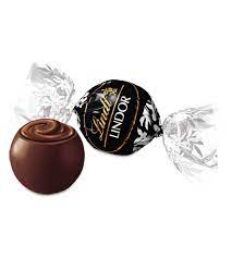 A wrapped and unwrapped Pick & Mix : Lindor Extra Dark 250/500g by Lindt with a dark chocolate shell and smooth filling sits beside a delightful white chocolate version, showcasing the exquisite variety of these luxurious truffles.