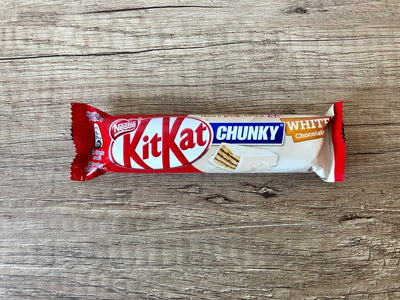 A Kitkat Chunky White 40gm chocolate bar with crunchy wafers on a wooden surface.