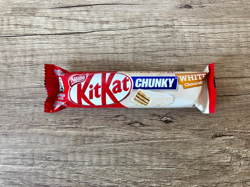 A Kitkat Chunky White 40gm chocolate bar with crunchy wafers on a wooden surface.